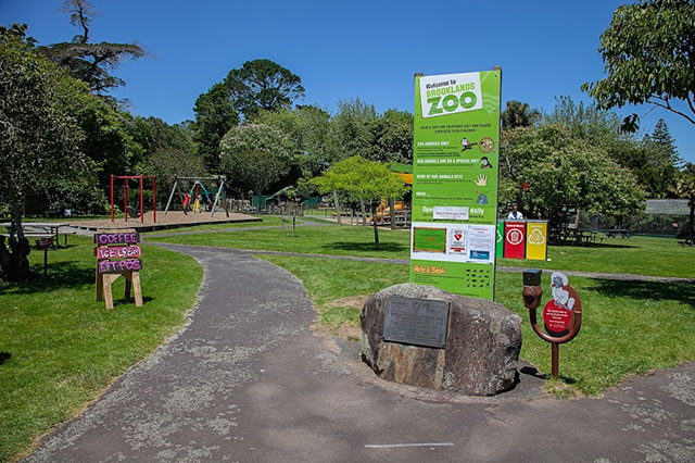 Green wayfinding sign in front of the playground at the zoo