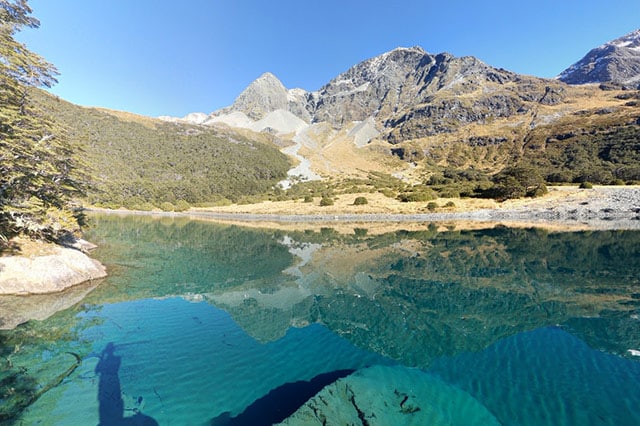 Incredibly blue lake surrounded by mountains and forest on a sunny day