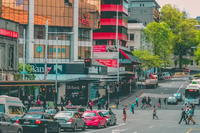 A busy intersection with cars, busses, and pedestrians in Auckland city.