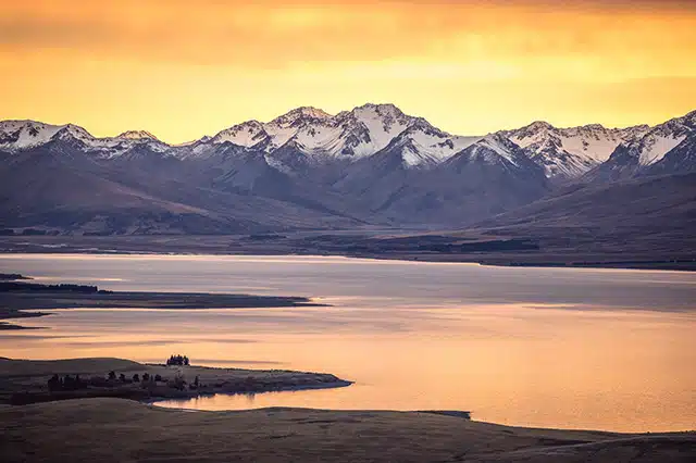 The orange sunrise over snow capped mountains