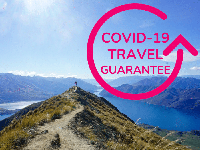 Covid-19 travel guarantee text with people on top of New Zealand mountain landscape