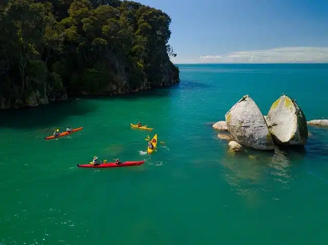 2 yellow and 2 red kayaks next to 'Split Apple Rock' a famous landmark in Nelson