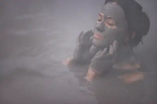 a women applying mud to her face in the mud pool