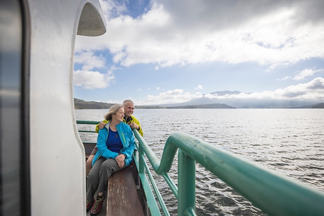 a couple sitting in a boat and looking out at the lake