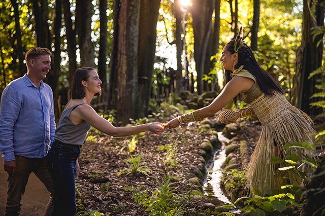 a maori local in traditional dress offering a visitor a gift