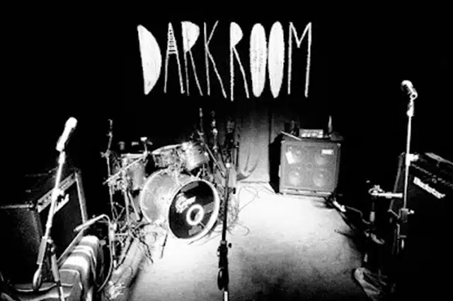 drums, microphones, and amps on the stage at darkroom