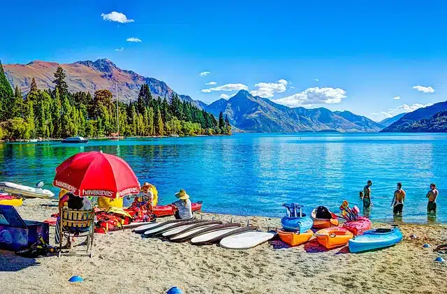 paddleboards and kayaks lining the sandy shore of the beach with mountains in the distance