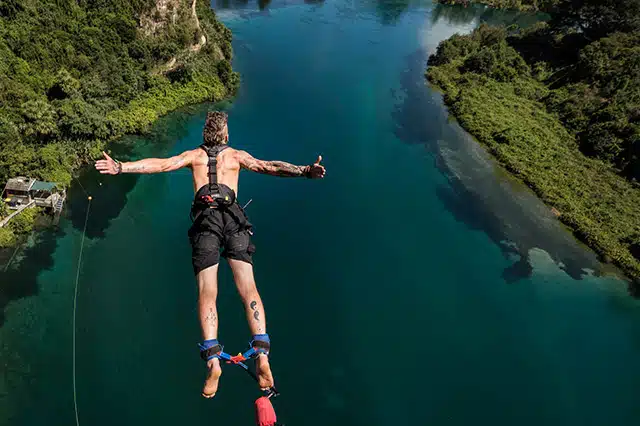 A man leaping out over the lake connected by the ankles to a bungy rope