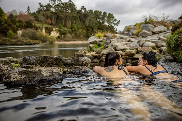 2 women lying in the hot springs looking out over the lake.