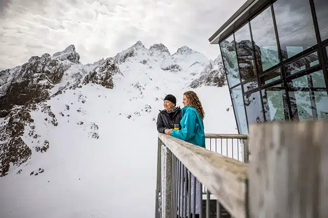 A couple standing on the balcony of a ski resort on Mt Ruapehu