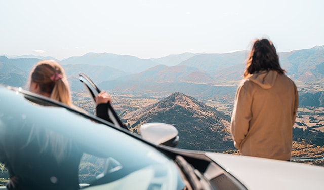 two people standing outside their GO Rentals vehicle overlooking the mountain landscape