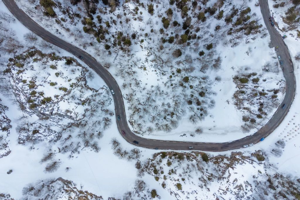 aerial view of cars driving on road in winter snow